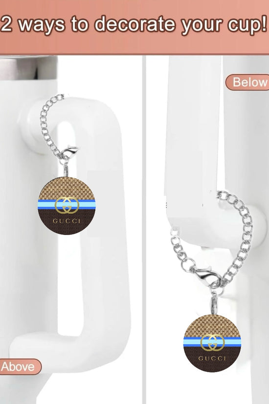 The Chanel Cup Charm by Kreative Kreationz is a white cup with a unique chain and handcrafted charm on the handle. The charm features a brown pattern with blue and black stripes, 