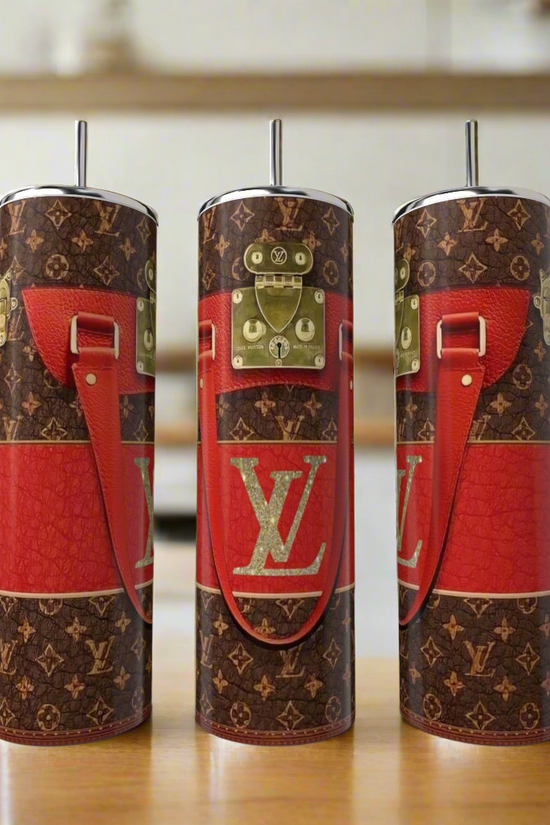 Three LV Red | Brown 20oz Tumblers by Kreative Kreationz, styled with brown and red tones, gold buckle accents, and red faux leather strap prints, are displayed on a kitchen counter for a touch of luxury drinkware.