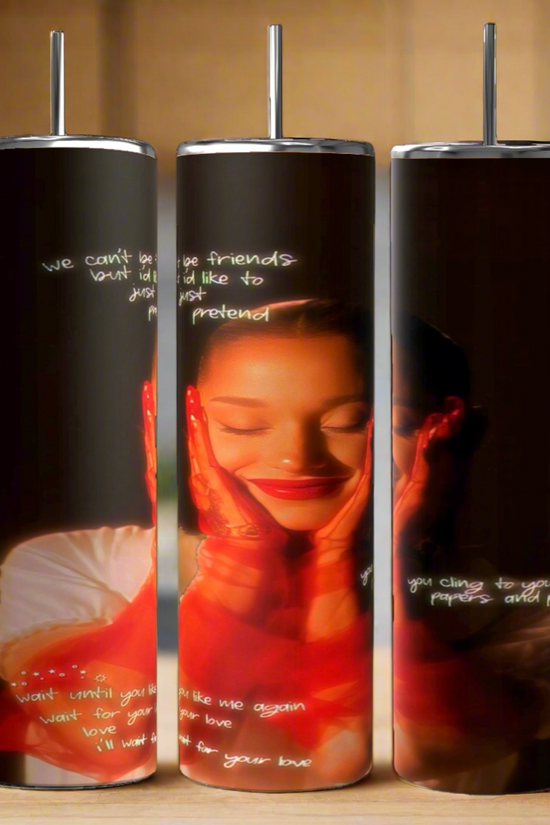 The External Sunshine | Ariana Grande 20oz Tumblers from Kreative Kreationz showcase a vibrant design of a person with closed eyes and hands on their face. White text in a stylized font overlays the image, enhancing the artistic feel against the dark background. Crafted for durability, these tumblers ensure a lasting appeal for any beverage experience.