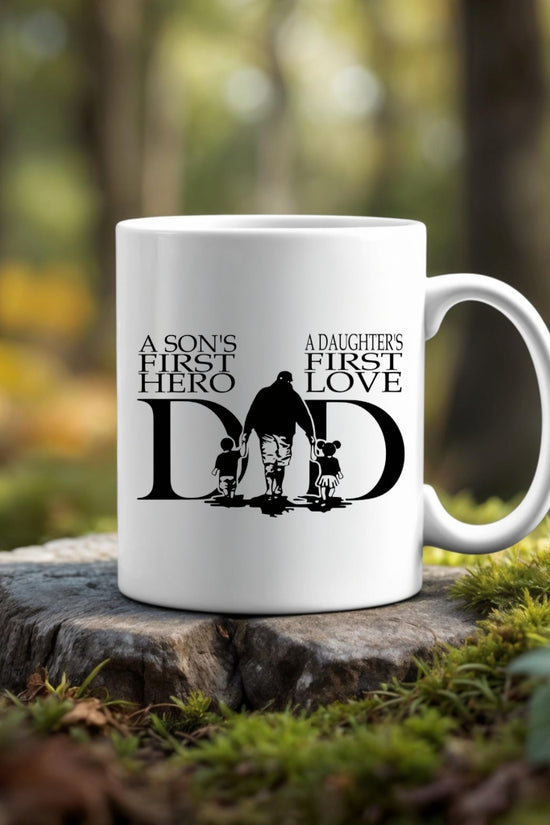 The A Sons First Hero - A Daughters First Love Dad Ceramic Mug by Kreative Kreationz features a seamless silhouette design with touching text—making it the perfect gift for dad. White ceramic mug displayed outdoors with forest greenery in the background.