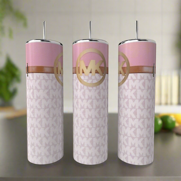 Three MK Pink Buckle 20oz Tumblers by Kreative Kreationz, in pink and white with metallic lids and straws, sit on a kitchen counter. Each stainless steel tumbler features a repeating "MK" pattern and a large gold "MK" logo.