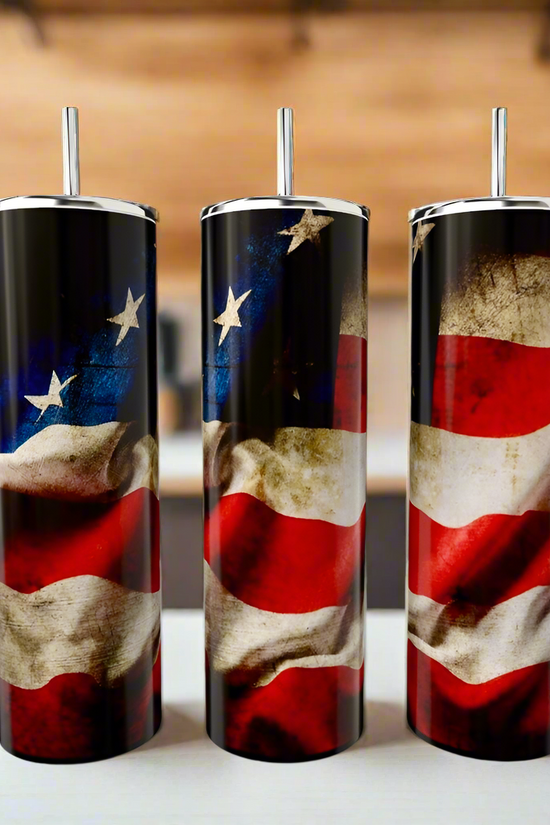 Three Kreative Kreationz American Flag 20oz Skinny Tumblers, each with a straw and vintage flag design, sit on a counter in front of a softly blurred indoor kitchen setting.