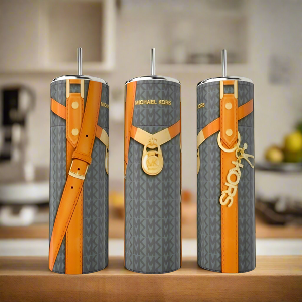 Three MK Beige 20oz Tumblers by Kreative Kreationz, featuring gold and brown designer-inspired accents and metallic details, are displayed on a kitchen counter with a blurred kitchen background.