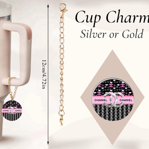 The handcrafted Chanel Charm Dangle by Kreative Kreationz features a circular pendant with a black and white pattern, pink accents, and hangs from a 12cm gold chain. Ideal for enhancing your beige cup, it comes in silver or gold options.