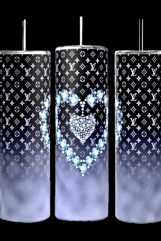 Three LV Designer 20oz Tumblers by Kreative Kreationz feature a tall, cylindrical design with spill-proof metallic lids and straws. They showcase a black and white designer pattern, with the middle tumbler adorned with a heart design crafted from blue flowers. Each tumbler transitions to a gradient foggy gray towards the bottom.