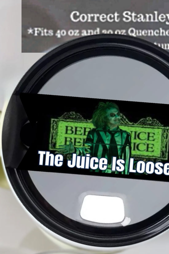 A close-up of a white tumbler with a black lid from Kreative Kreationz. The Beetlejuice Stanley Lid Topper showcases a green-haired character on a neon background and the text 