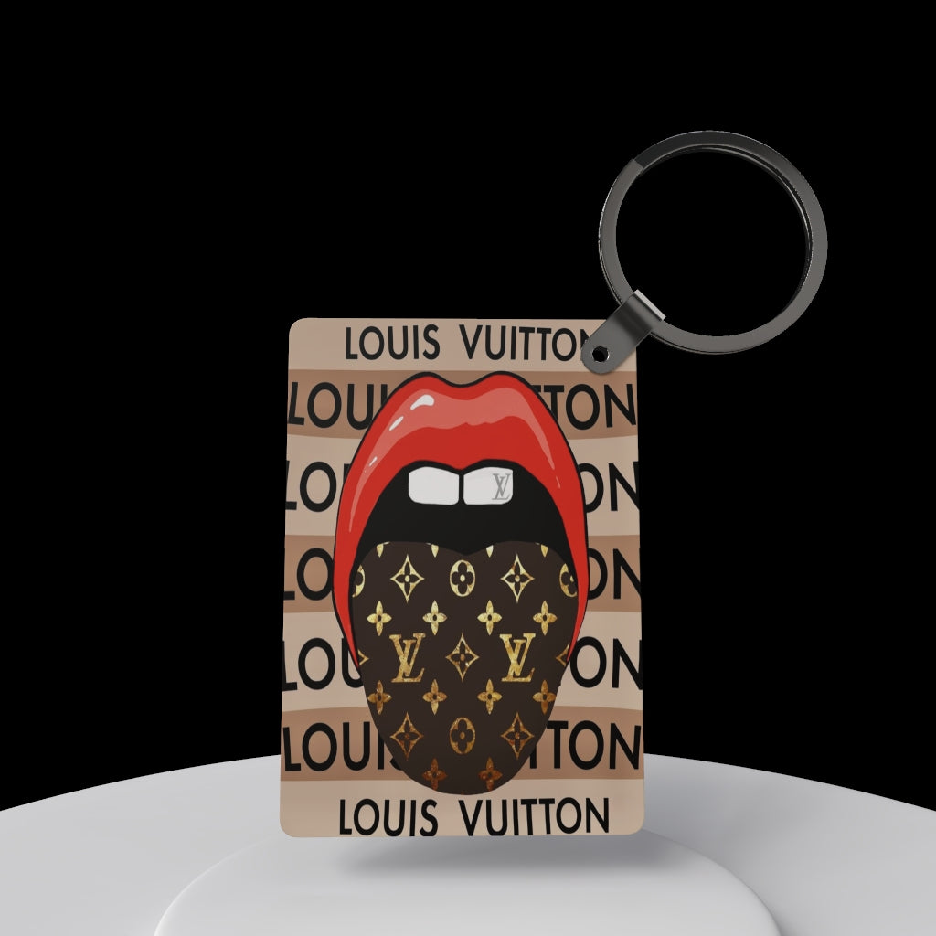 The LV Inspired Keychain by Kreative Kreationz features red lips with a tongue behind a Louis Vuitton-patterned mask on a beige "LOUIS VUITTON" print—an ideal gift for fashion enthusiasts.