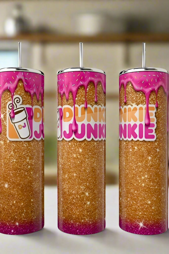 Three Kreative Kreationz Dunkin Junkie 20oz Tumblers with glitter, pink dripping tops, bold “Dunkin Junkie” text, and a coffee cup icon are displayed on a kitchen counter with a blurred background.
