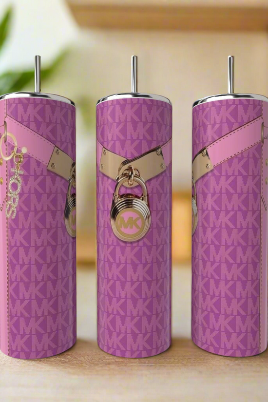 Three tall Kreative Kreationz MK 20oz Tumblers in pink with metal straws sit on a kitchen counter. Each features a pink and gold MK pattern with lock and keychain charms. The softly blurred background highlights the luxury drinkware.