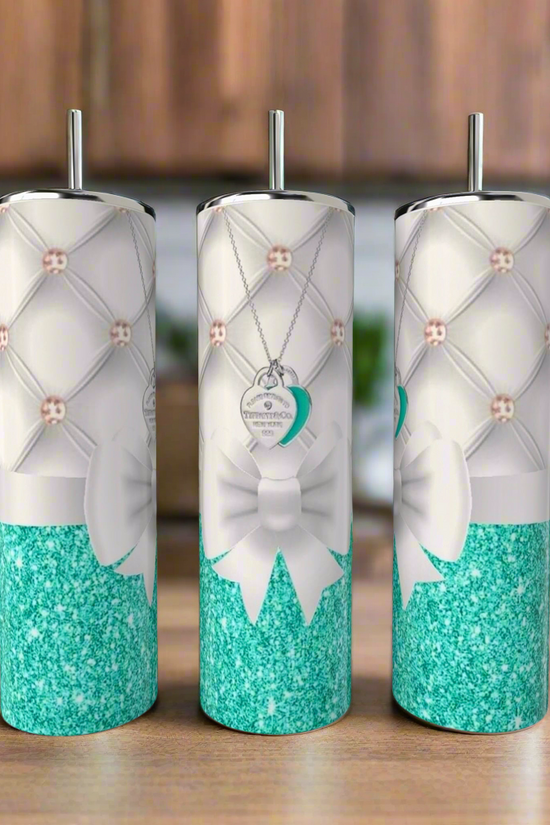 Three Tiffany 20oz Tumblers by Kreative Kreationz, featuring teal glitter bottoms, white quilted patterns, white bows, and heart-shaped tag designs, are displayed on a wooden surface with a chic Tiffany theme.