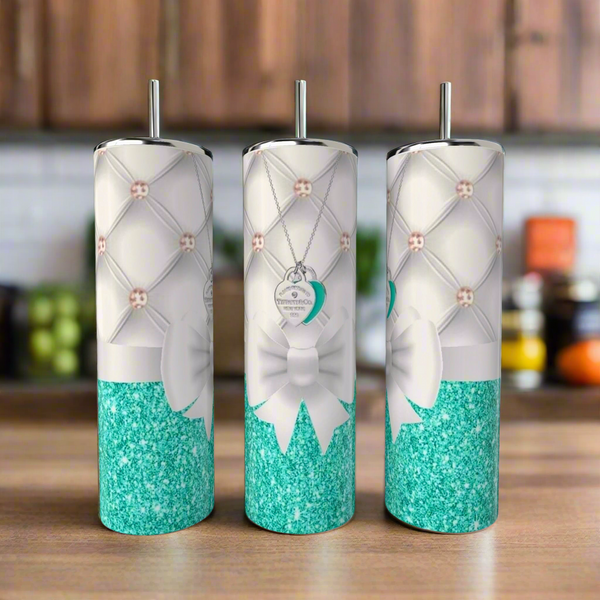 Three Tiffany 20oz Tumblers by Kreative Kreationz, featuring teal glitter bottoms, white quilted patterns, white bows, and heart-shaped tag designs, are displayed on a wooden surface with a chic Tiffany theme.