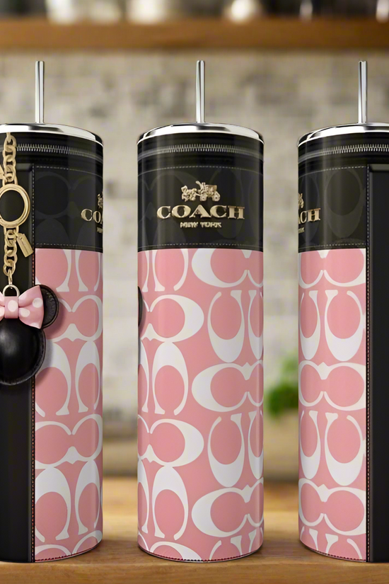 Three Kreative Kreationz Coach Pink Minnie 20oz Skinny Tumblers with pink and white logo patterns, black accents, straw lids, and keychains sit on a kitchen counter—stylish luxury drinkware for any setting.