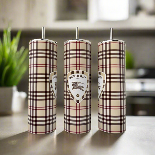 Three 20oz Skinny Tumblers by Kreative Kreationz, inspired by Burberry’s plaid, stand on a kitchen counter—stylish and elegant drinkware with blurred plant and stove in the background.