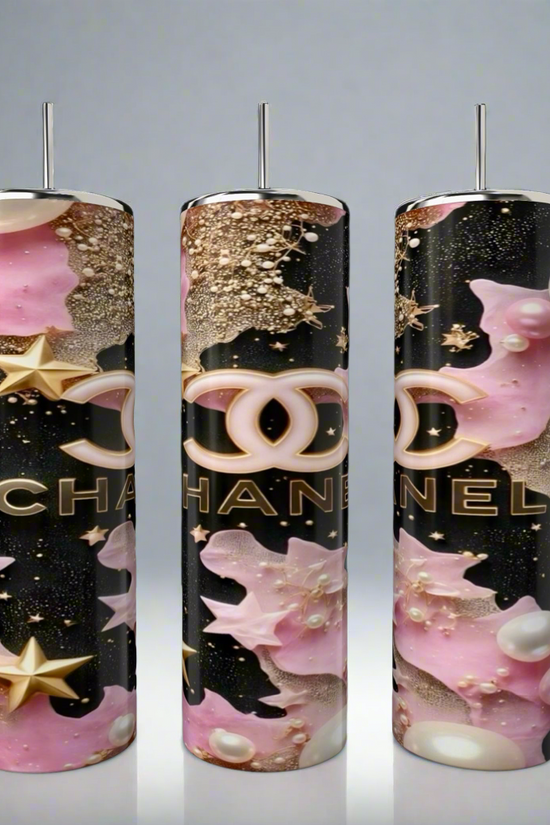 The Chanel 20oz Skinny Tumbler by Kreative Kreationz features three tall, glossy tumblers with metallic rods, pink and gold stars and Chanel logos, set against a black background—showcasing luxury stainless steel drinkware artistry.
