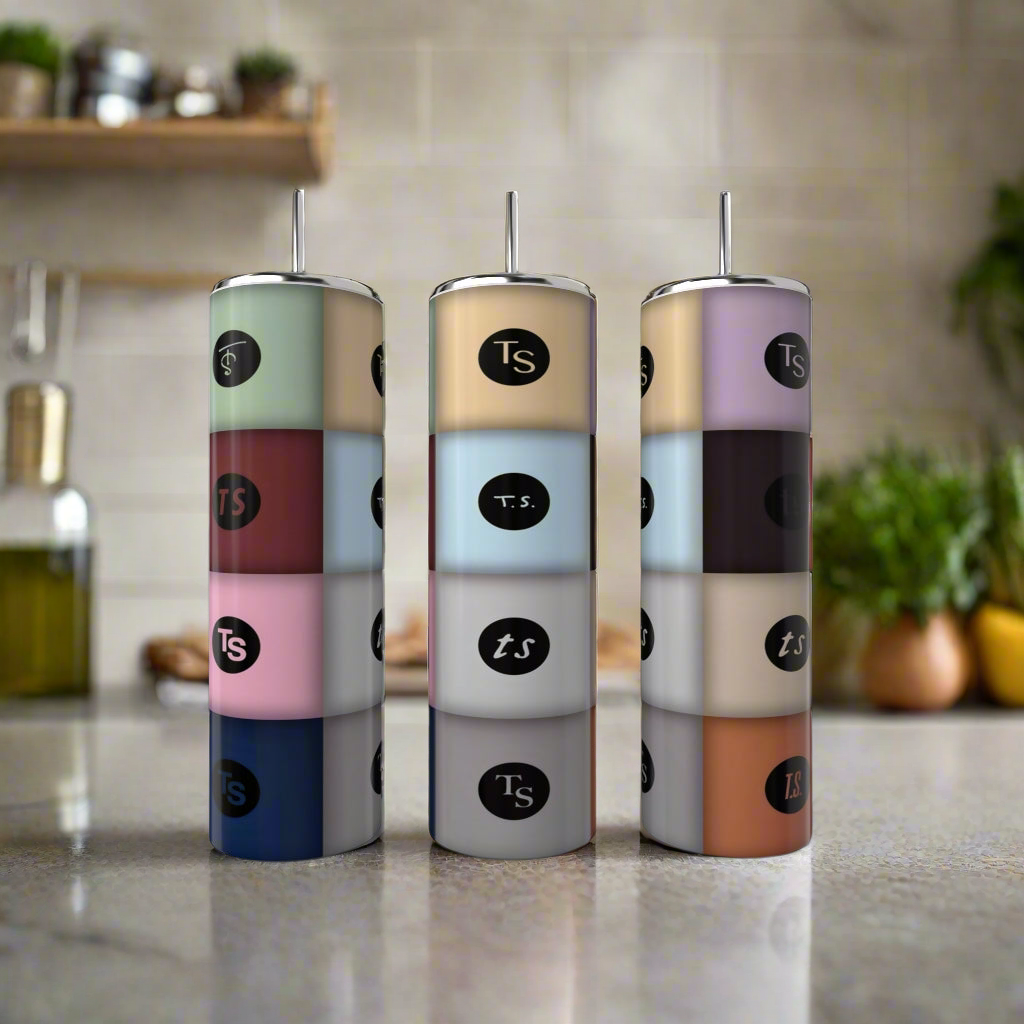 Three pastel, cylindrical spice containers labeled "TS" stand next to a Kreative Kreationz TA12 | Taylor Swift 20oz Tumbler on a kitchen countertop, with herbs and other items softly blurred in the background.