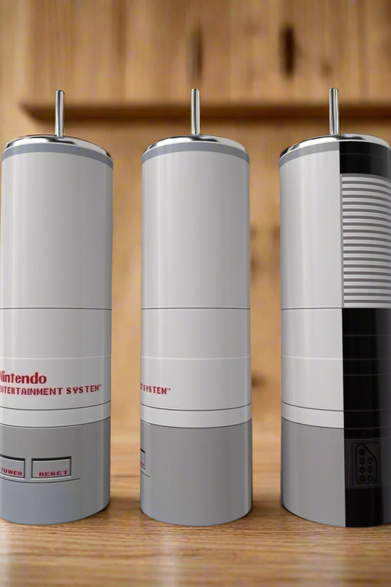 Three Kreative Kreationz Nintendo Collection 20oz Tumblers, styled after classic NES consoles, sit on a wooden counter with blurred kitchen shelves behind—ideal for fans wanting standout, luxury drinkware.