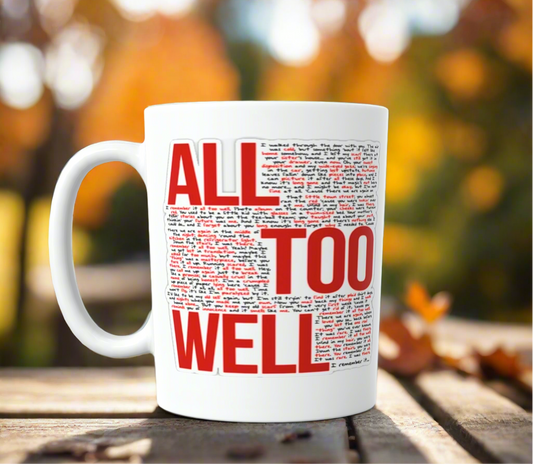 The ALL TOO WELL LYRICS- RED Era-Taylor Swift Ceramic Mug by Kreative Kreationz, featuring bold red and black text, rests on a wooden outdoor table amid blurred autumn trees with orange leaves in the background.