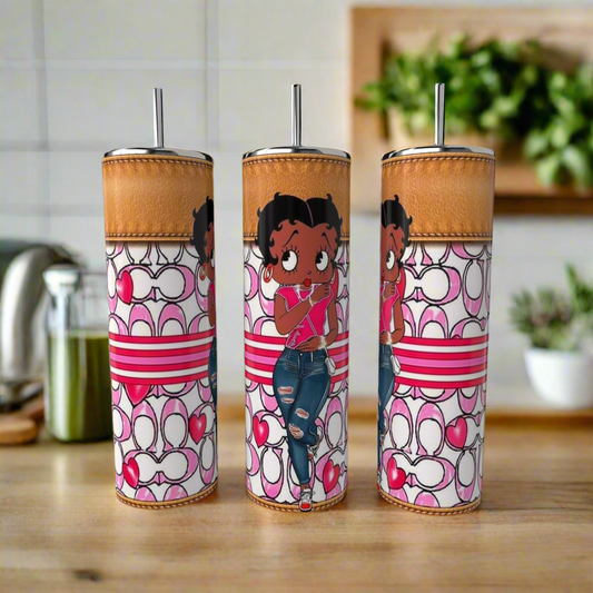 The Betty B Coach 20oz Skinny Tumblers by Kreative Kreationz feature a cartoon girl in pink and ripped jeans with heart, stripe, and loop designs. Eco-friendly stainless steel drinkware displayed on a wooden kitchen counter.