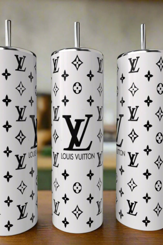 Three tall Kreative Kreationz Black & White LV Basic 20oz tumblers with metal straws rest on wood. Each features the black Louis Vuitton logo and monogram pattern, with a blurred kitchen in the background.