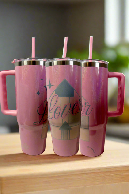 Three pink Kreative Kreationz stainless steel tumblers with handles and straws are displayed on wood. The center 