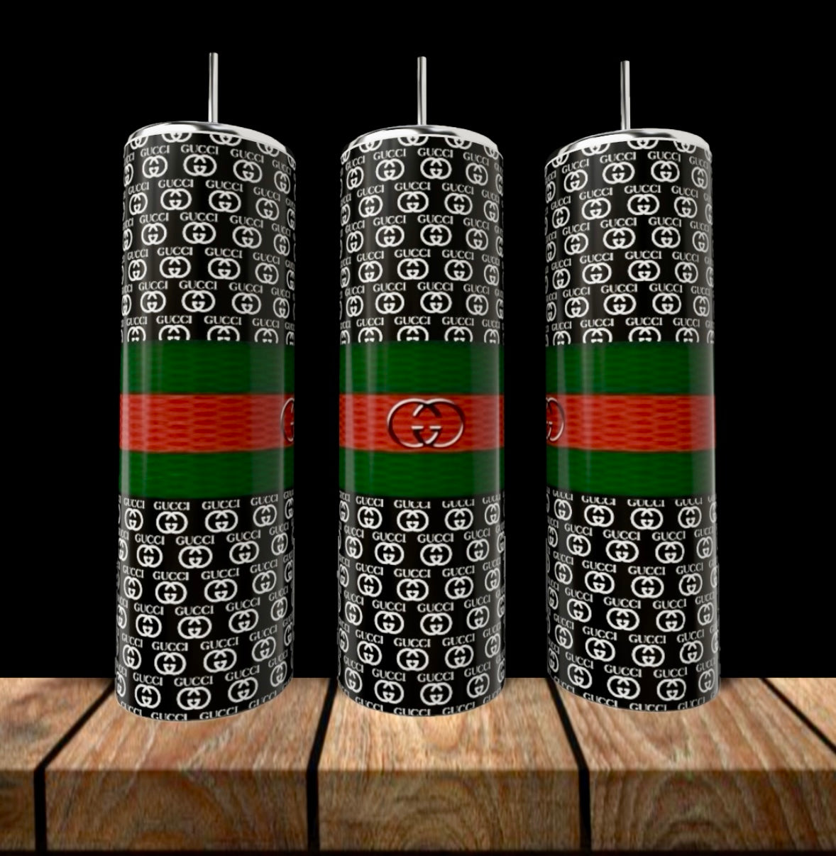 Three GUCCI 20oz Skinny Tumblers by Kreative Kreationz with black backgrounds, white "GG" logos, green and red stripes, silver straws, and central circular emblems stand on a wooden surface—stylish luxury drinkware.