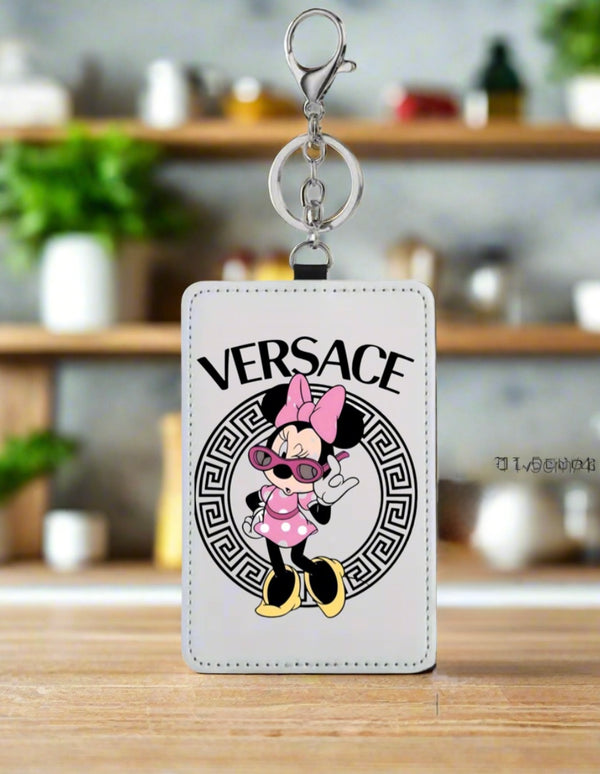 A stylish card wallet by Kreative Kreationz features a white tag with a cartoon mouse in sunglasses, pink bow, and outfit in front of a black Versace-style logo. "VERSACE" appears above the character—perfect for minimalist style lovers.