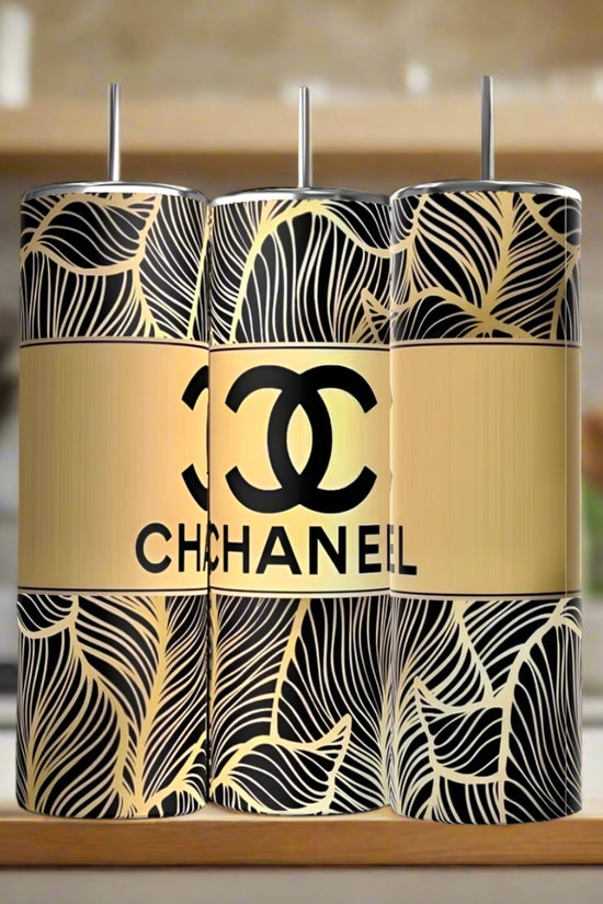 Three 20oz stainless steel tumblers with black and gold leaf patterns are side by side. The center is the 