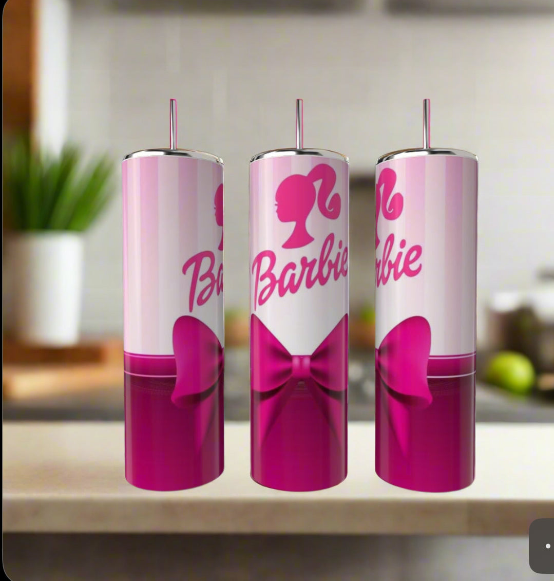 Three Barbie 20oz Tumblers by Kreative Kreationz, each with a pink bow and Barbie logo featuring a woman's silhouette, are lined up on a kitchen counter. The tumblers have straws and the pink-and-white design stands out against a blurred background.