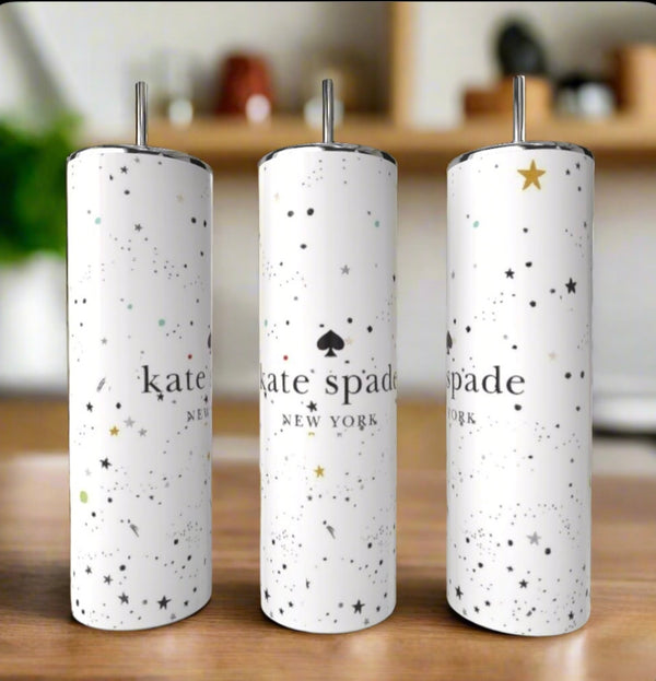 Three white Kate Spade Sparkle 20oz Skinny Tumblers by Kreative Kreationz, with silver lids and straws and a scattered stars-and-dots design, showcase the “kate spade NEW YORK” logo on a stylish wooden surface.