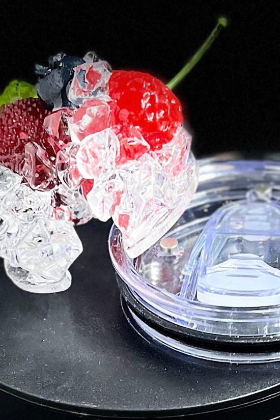 A lineup of CÎROC vodka cans in various flavors including original, mango, red berry, coconut, watermelon, and peach is beautifully arranged on an outdoor surface with a green hedge and blue sky background. Each can is paired with a chic 20oz Ciroc Tumbler with 3D Lid Topper by Kreative Kreationz.