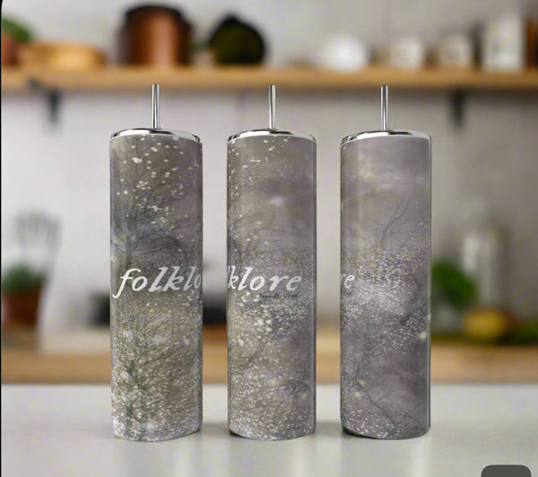 Three Kreative Kreationz Taylor Swift Folklore 20oz stainless steel tumblers with straws, gray forest design, and “folklore” in white script are displayed on a kitchen counter with blurred shelves in the background.