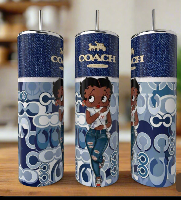 The Betty Boop 20oz Tumbler by Kreative Kreationz features a cartoon woman in jeans and a white top on a blue and white patterned background, silver straw, "COACH" branding, denim texture, and luxury drinkware appeal.