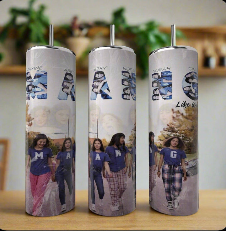 The Kreative Kreationz Ginny & Georgia MANG Girls 20oz Tumbler showcases a collage of four girls in "M", "A", "N", and "G" shirts against a blurred backdrop, blending eco-friendly luxury with personalized style.