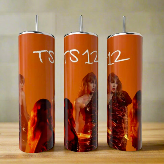Three TS12 | Orange Taylor Swift 20oz tumblers by Kreative Kreationz, featuring a woman in a shiny dress, orange-red background, and "TS 12" in white, stand on a wooden surface with silver straws.