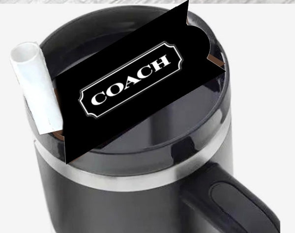 A black mug by Kreative Kreationz, viewed from above, holds a white rolled paper and a Coach | Stanley Lid Plate/Topper with a Coach-branded black card inside.