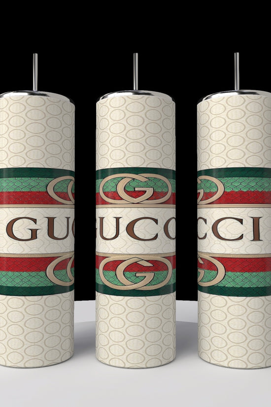 Three white candles with the Gucci logo stand on a white surface against a black background. Each displays the iconic green and red stripes, reflecting the design of Kreative Kreationz's new Gucci 20oz Tumbler collection.