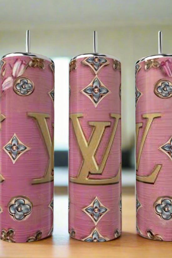 Three LV Pink BlueJeweled 20oz Tumblers by Kreative Kreationz, featuring pink backgrounds, gold LV logos, and floral and geometric patterns, are displayed on a wooden surface in a bright, modern kitchen.