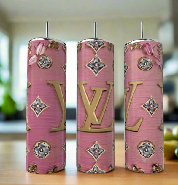 Three LV Pink BlueJeweled 20oz Tumblers by Kreative Kreationz, featuring pink backgrounds, gold LV logos, and floral and geometric patterns, are displayed on a wooden surface in a bright, modern kitchen.