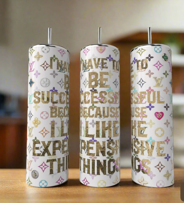 Kreative Kreationz's LV I Have To Be Successful Because I Like Expensive Things 20oz tumbler features a tall, cylindrical shape, a straw, and colorful Louis Vuitton-inspired patterns with gold text.