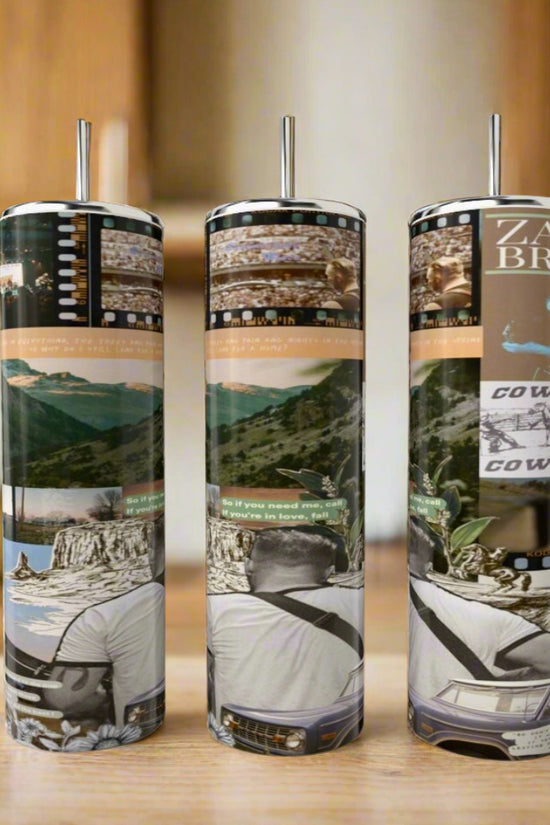 Three eco-friendly Kreative Kreationz Zach Bryan 20oz Tumblers with metal straws feature luxury-inspired designs: collage-style mountains, a man outdoors, song lyrics, and film strips—all set on a kitchen’s wooden table.
