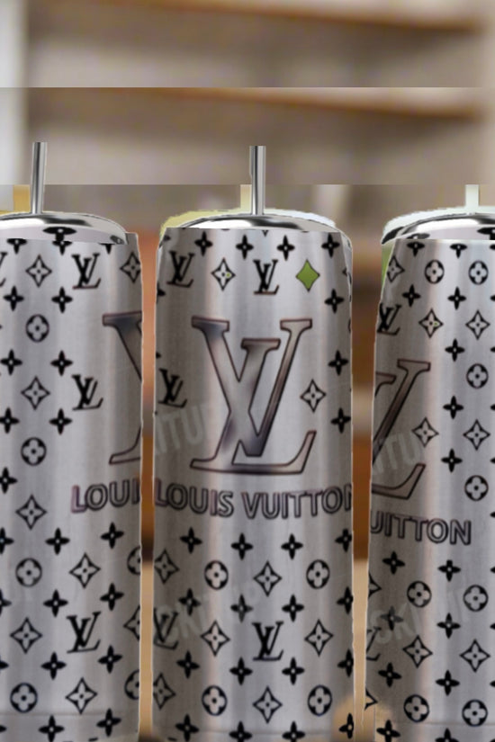 Three Kreative Kreationz LV Silver Stainless Steel Inspired 20oz Tumblers with silver straws sit on a wooden table. Each features a luxury gray Louis Vuitton-style monogram and logo against a softly blurred background.