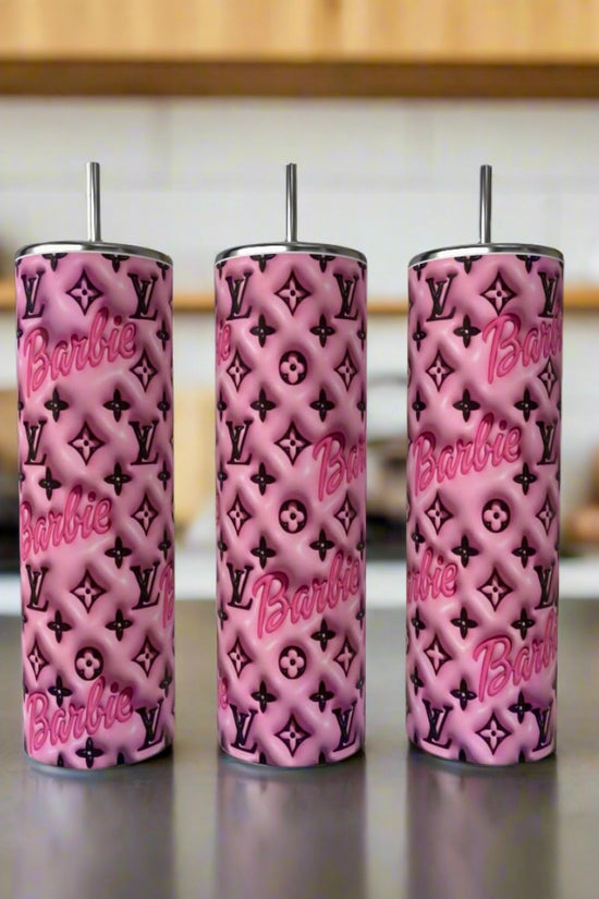 Three tall Barbie LV 20oz Tumblers by Kreative Kreationz stand on a counter, each with metal straw and a chic pattern blending Barbie and Louis Vuitton symbols. The softly blurred kitchen background adds an elegant touch.