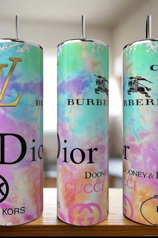Three 20oz Designer Tumblers by Kreative Kreationz, featuring pastel tie-dye designs and luxury-inspired logos, are shown with straws on a wooden surface.