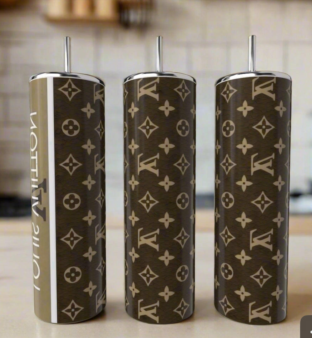 Three Kreative Kreationz LV Brown 20oz Tumblers with silver lids and straws sit on a kitchen counter, each featuring a brown and beige monogram—an elegant upgrade for your luxury drinkware collection.