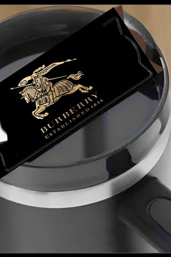 A Burberry | Stanley Lid Plate/Topper by Kreative Kreationz sits atop a black mug with a white straw, offering a chic designer touch—perfect for Stanley tumbler fans who love standout style.