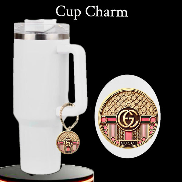 A white travel mug with a handle appears against a black background, adorned with the Kreative Kreationz Gucci | Pink Cup Charm featuring gold, pink, and red patterns and a central "GG" logo. The text above reads "Cup Charm.