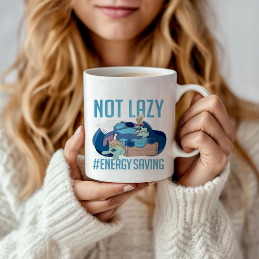 A woman in a white sweater holds the Stitch 15oz Mug by Kreative Kreationz, featuring a cartoon sloth lounging with the words “NOT LAZY #ENERGY SAVING” in a vibrant sublimation design close to her face.