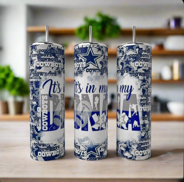 Three Kreative Kreationz Cowboys | Its In My DNA 20oz Skinny Tumblers, featuring Dallas Cowboys logos and blue-and-white "It's In My DNA" designs, sit on a kitchen counter with blurred plants in the background.