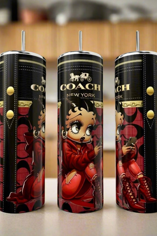 Three tall, cylindrical Kreative Kreationz Betty Boop | 20oz Tumblers, decorated with cartoon Betty Boop in a red outfit, are displayed on a countertop with a blurred kitchen background. These eco-friendly tumblers add charm to any setting.