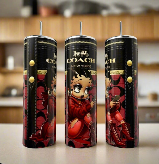 Three tall, cylindrical Kreative Kreationz Betty Boop | 20oz Tumblers, decorated with cartoon Betty Boop in a red outfit, are displayed on a countertop with a blurred kitchen background. These eco-friendly tumblers add charm to any setting.